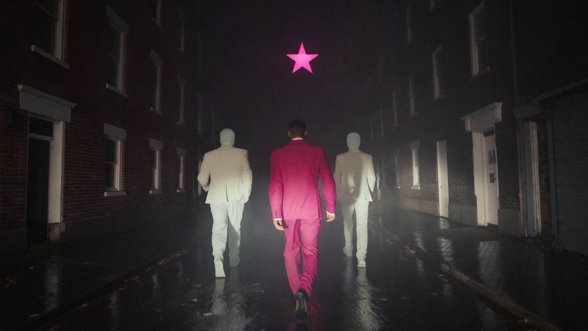 A man in a pink suit walking a rain slick rowhouse street at night, two pale silhouettes behind him, a pink star above